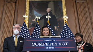 Speaker of the House Nancy Pelosi stands behind a podium labeled "America Competes Act of 2022."