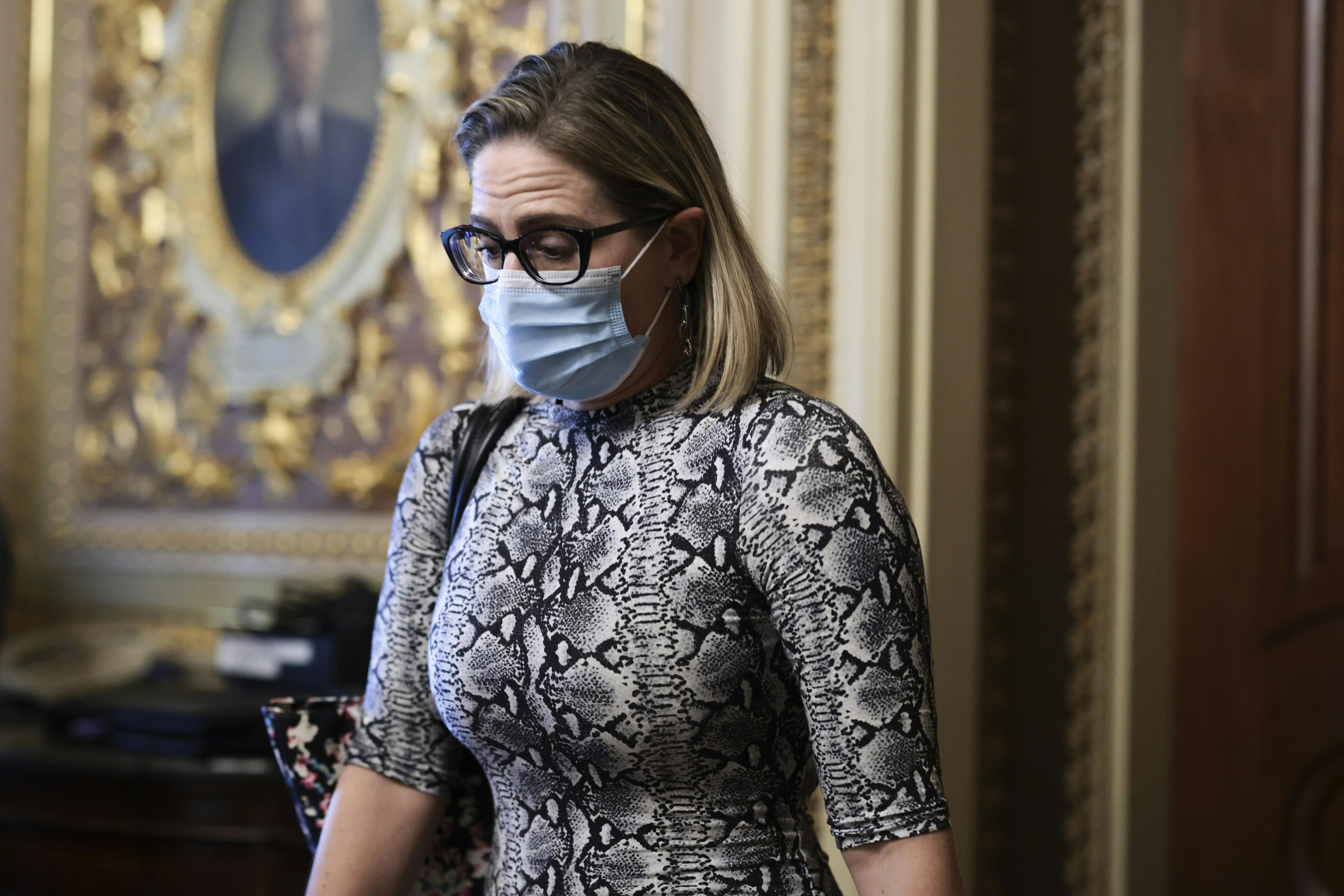A close-up of a masked Kyrsten Sinema