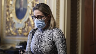 A close-up of a masked Kyrsten Sinema