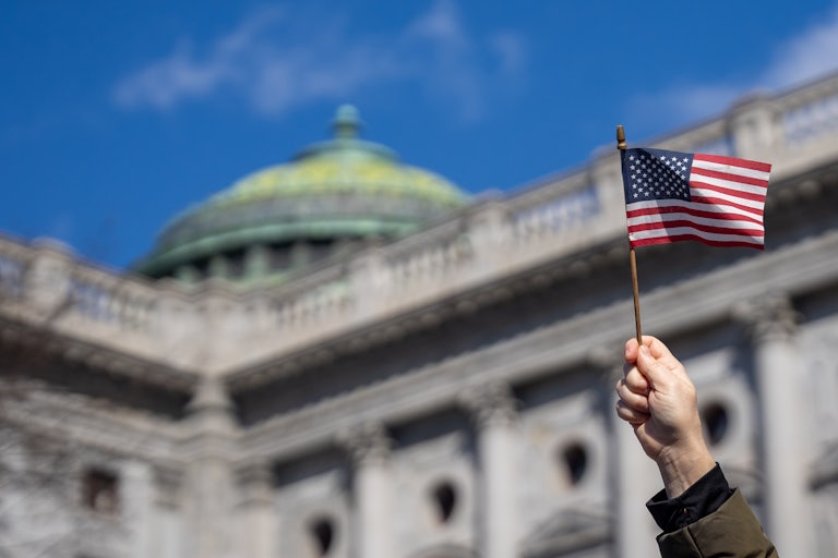 A person holds up an American flag outside the Pennsylvania state Capitol