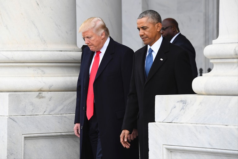 Donald Trump and Barack Obama look down while standing next to each other outside the White House