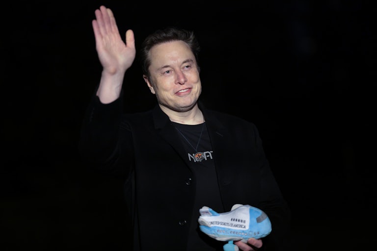 Elon Musk waves while holding an Air Force One stuffed toy.