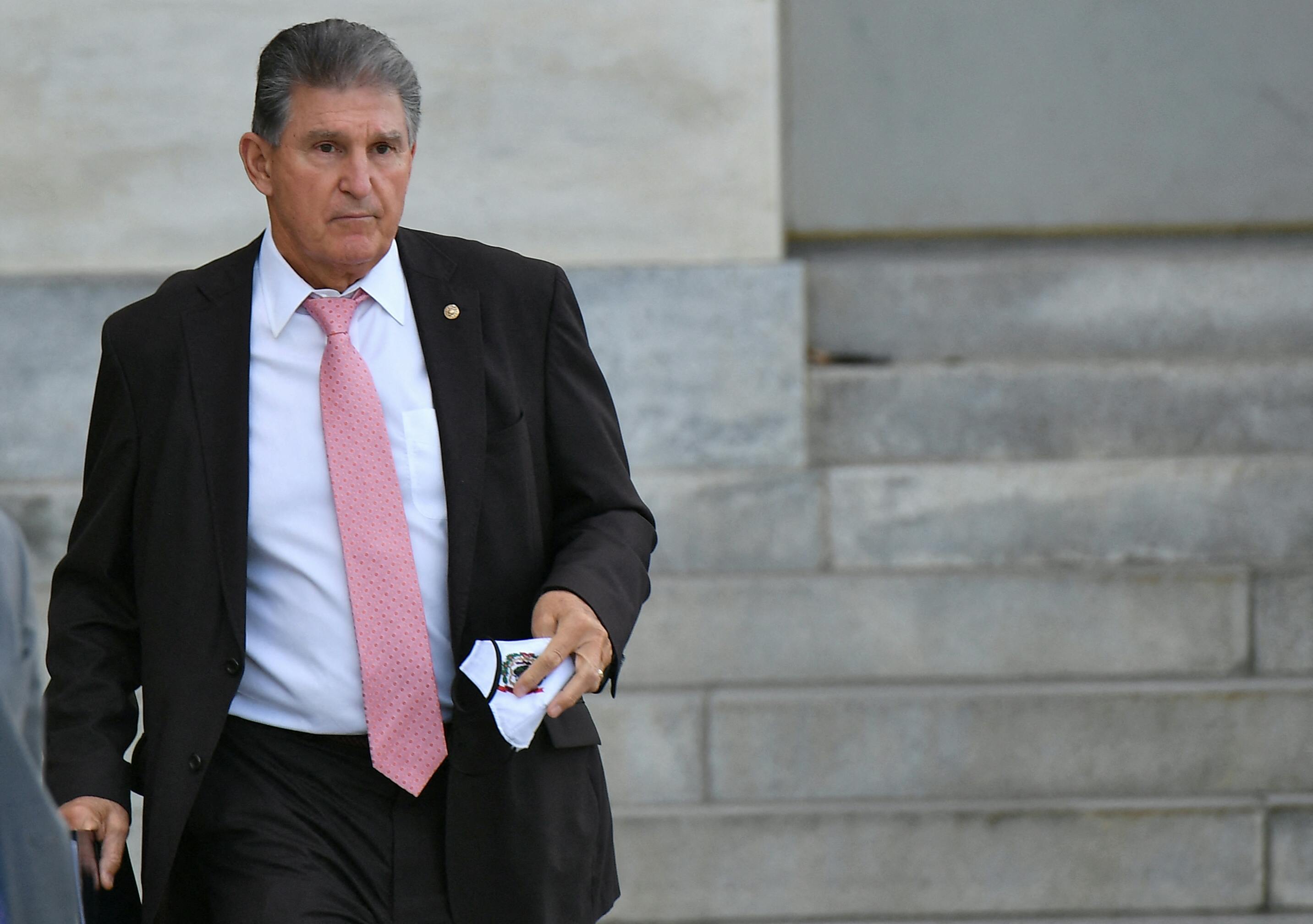 Senator Joe Manchin stands outside holding a napkin.