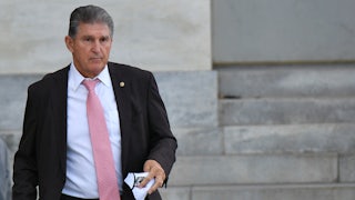 Senator Joe Manchin stands outside holding a napkin.