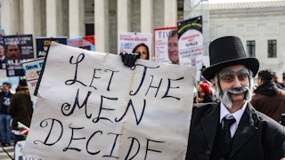 A demonstrator in historical costume holds a sign reading "let the men decide"