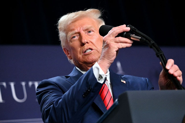 Trump grasps a microphone at a lectern.