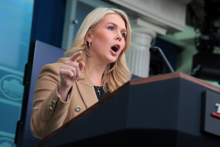 Karoline Leavitt yells at the podium in the White House press briefing room.