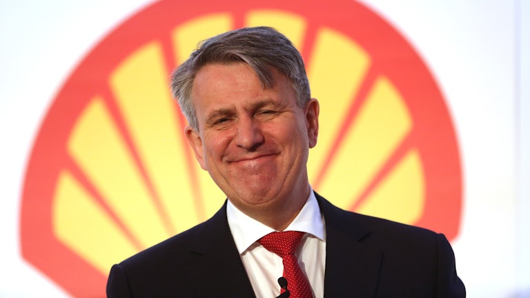 Ben van Beurden smiles in front of a Shell logo.