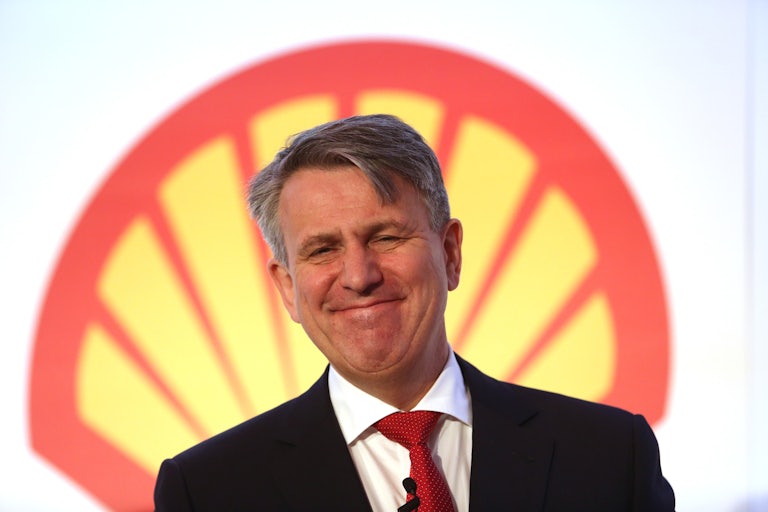 Ben van Beurden smiles in front of a Shell logo.