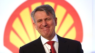Ben van Beurden smiles in front of a Shell logo.