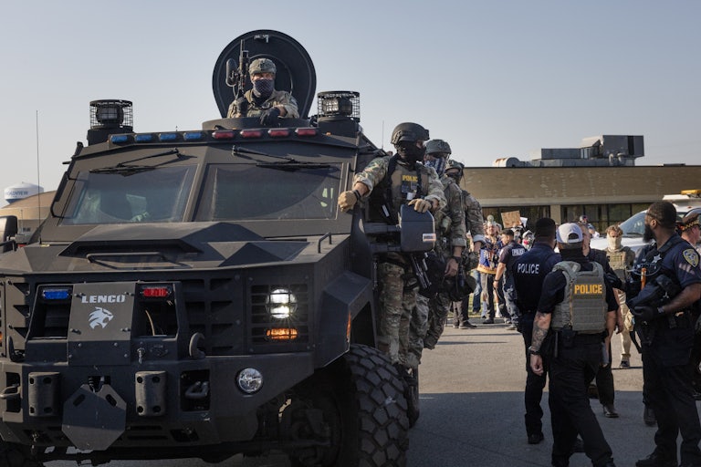 Federal law enforcement agents ride an armored vehicle through demonstrators during a protest outside an ICE facility in Broadview, Illinois.