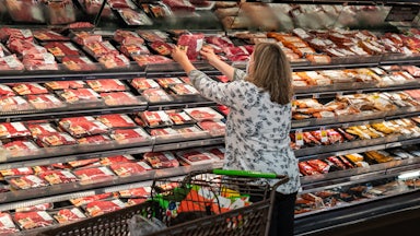 A shopper reaches for a package of meat in a supermarket.
