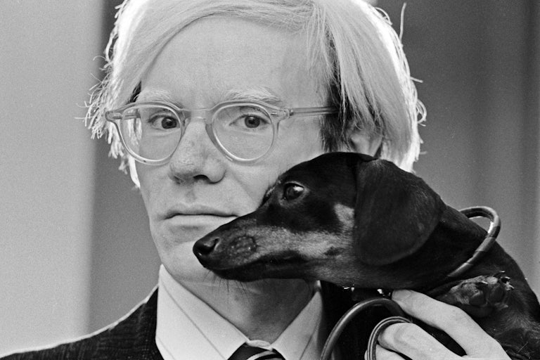 Artist Andy Warhol poses with his dauschund, Archie.