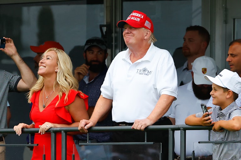 Donald Trump and Marjorie Taylor Grene smile while overlooking a balcony