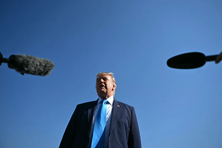 Donald Trump speaks as reporters hold boom microphones out towards him