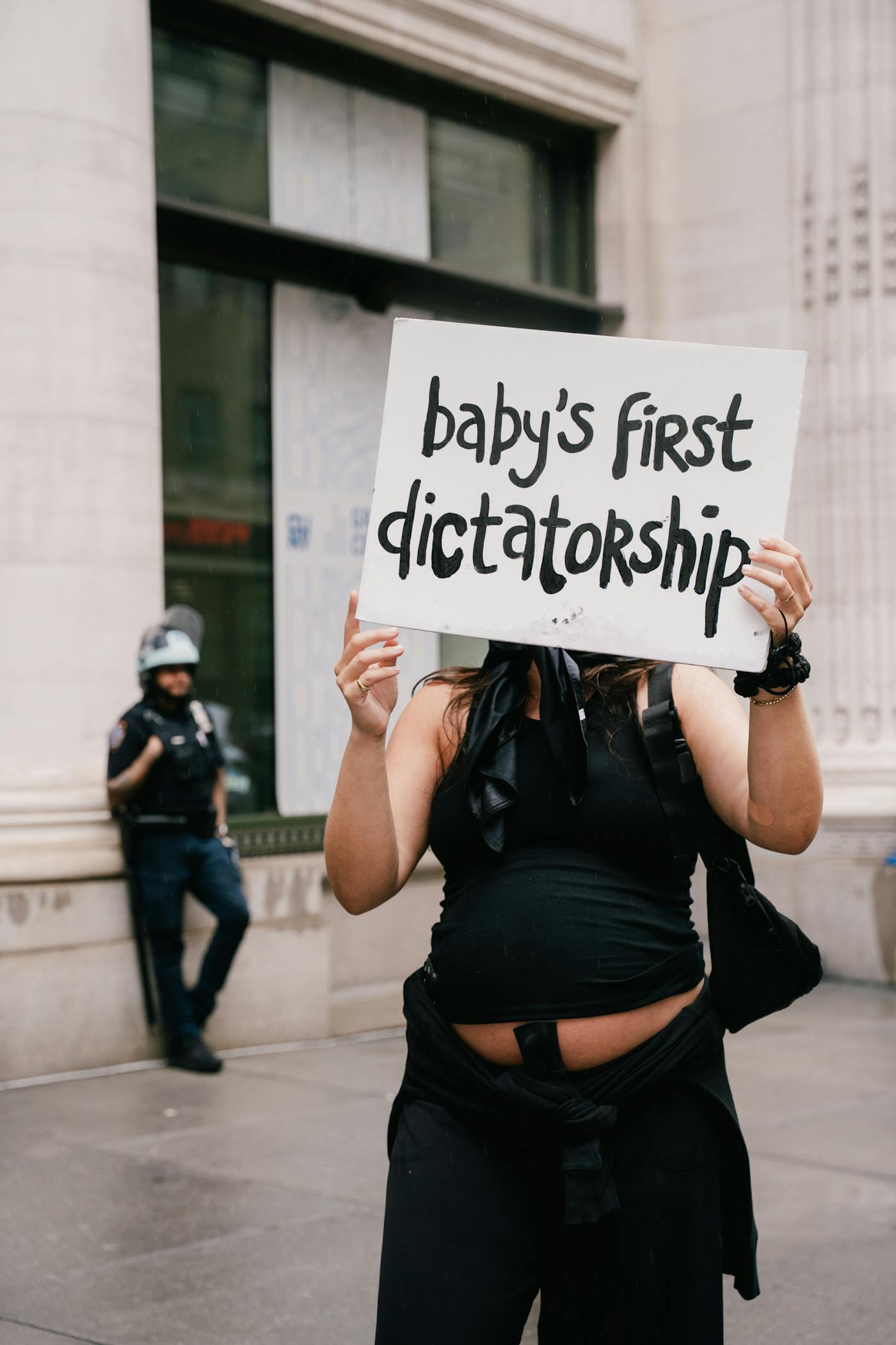 A protesters holding a homemade cardboard sign that says Baby's first Dictatorship Ice in New York City on Sunday at the No Kings event 