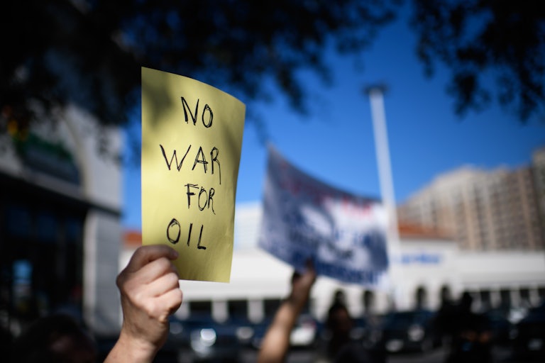 A protester holds up a sign that says, "No war for oil"