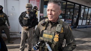 CBP Chief Gregory Bovino stands with masked agents outside a gas station store
