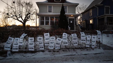 Dozens of signs reading "ICE Out Now" decorate the front of a Minneapolis home