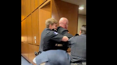 Two police officers and Senator Tim Sheehy all try to force Marine veteran Brian McGinnis out of a doorway.