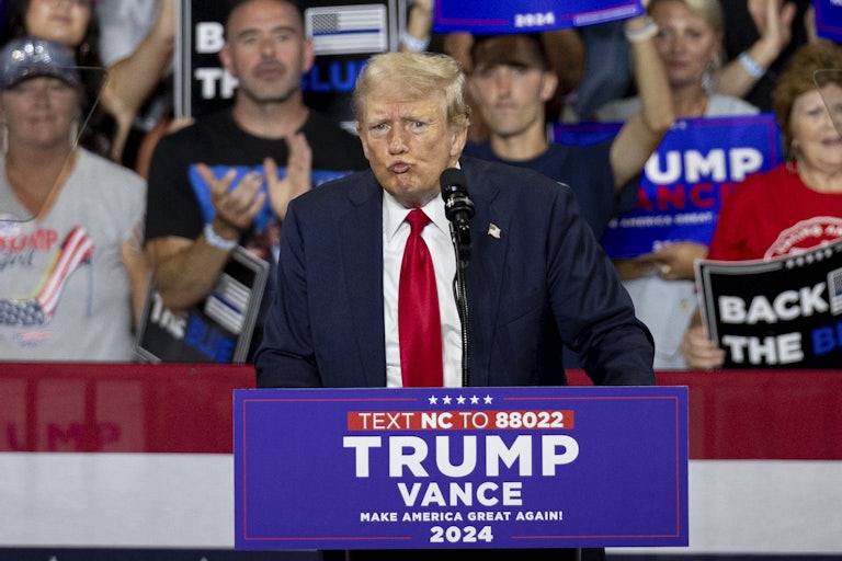 Donald Trump purses his lips while speaking at a rally