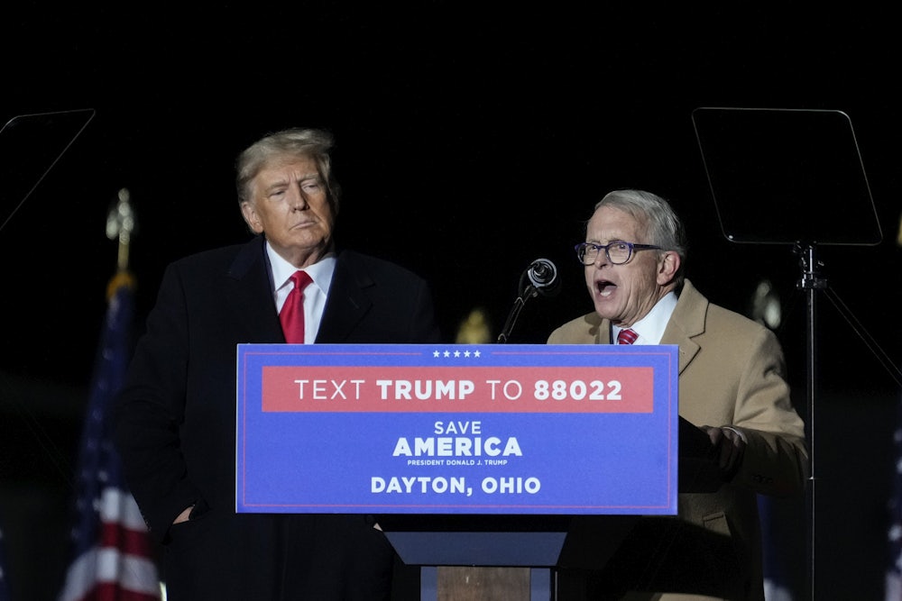 Mike DeWine speaks at a lectern as Donald Trump watches.