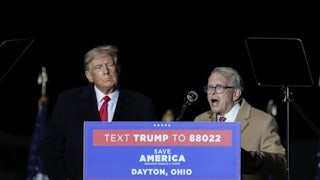 Mike DeWine speaks at a lectern as Donald Trump watches.
