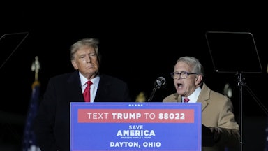 Mike DeWine speaks at a lectern as Donald Trump watches.