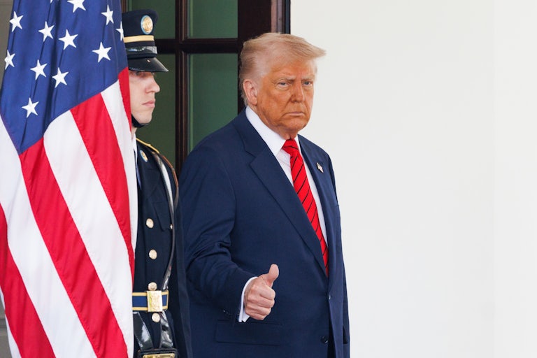 Donald Trump gives a thumbs up while standing outside the White House