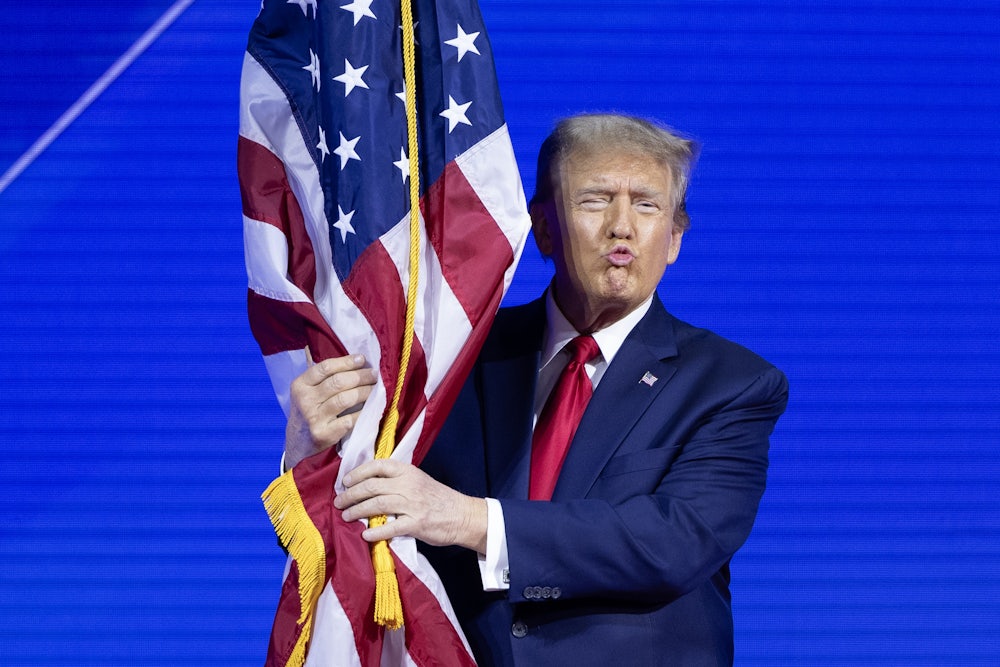 Donald Trump hugs the American flag while walking on stage ahead of his remarks at the Conservative Political Action Conference.