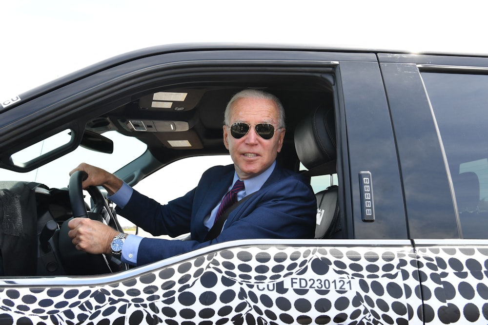 Joe Biden wearing sunglasses and looking out the window of a Ford F150 truck.