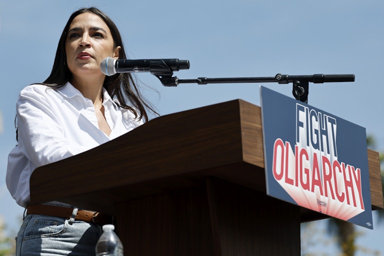 Representative Alexandria Ocasio-Cortez speaks at a lectern that says "Fight Oligarchy."
