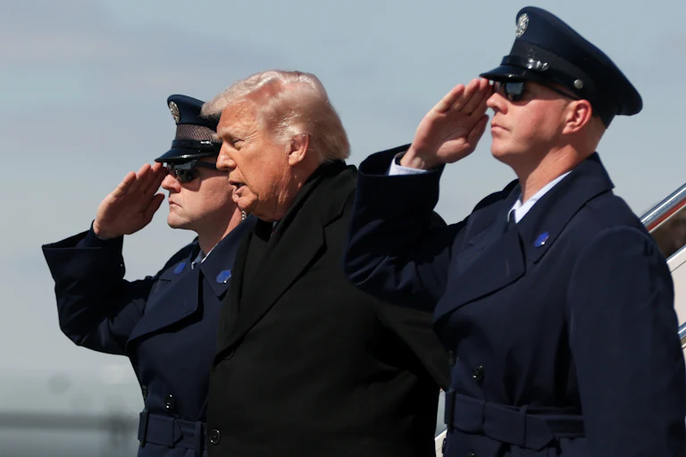 Donald Trump stands between two saluting officers during a dignified transfer ceremony