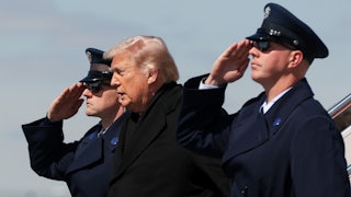 Donald Trump stands between two saluting officers during a dignified transfer ceremony