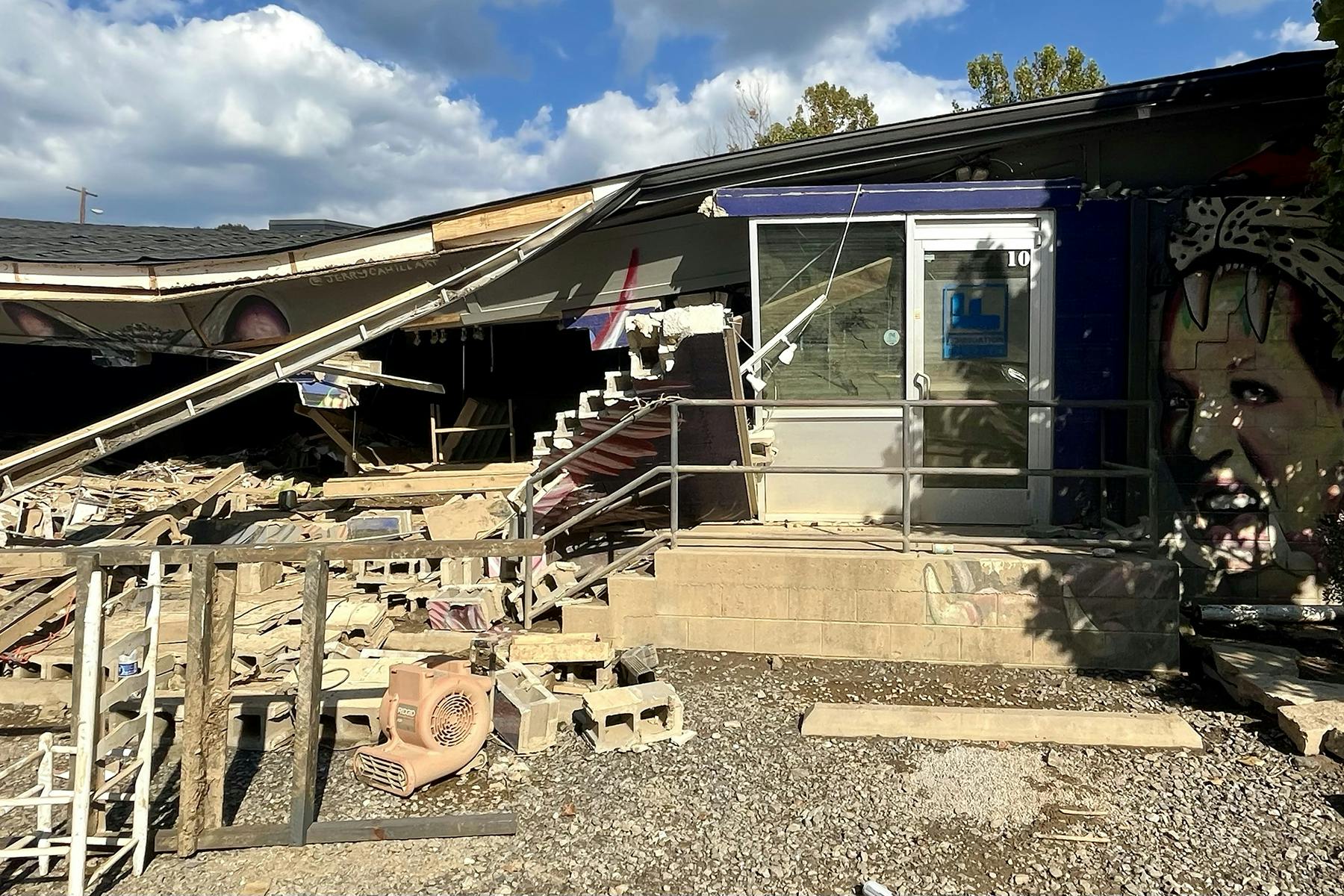 A partially collapsed roof hangs over debris from a damaged building.