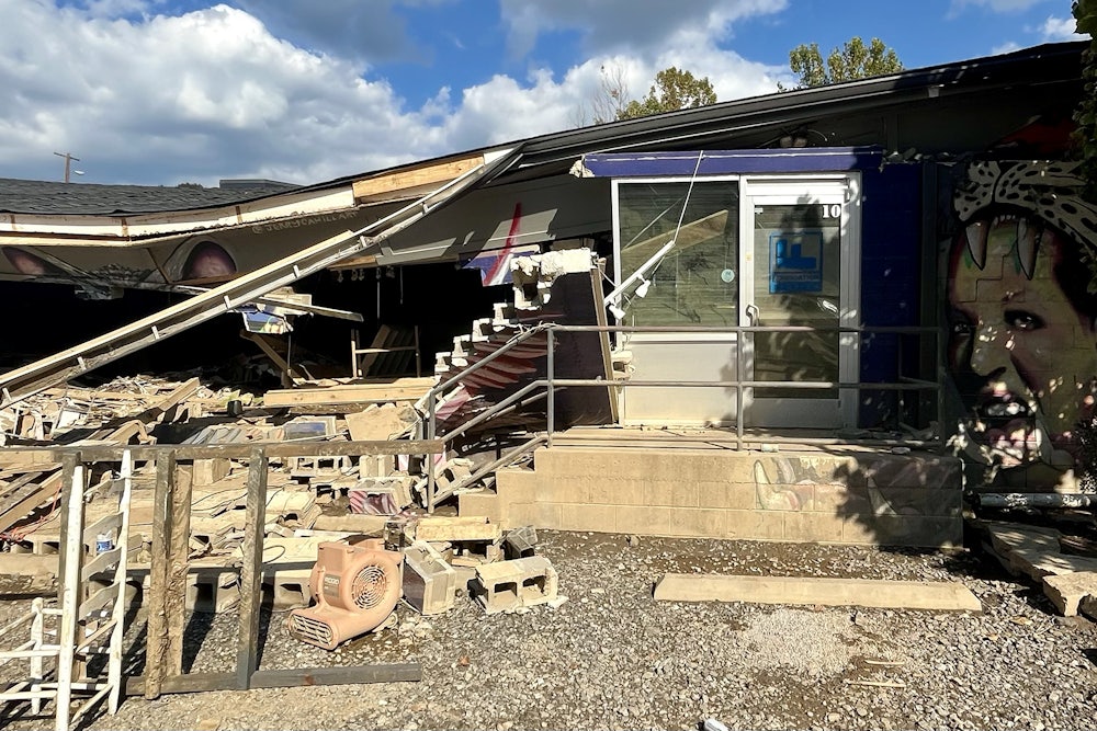 A partially collapsed roof hangs over debris from a damaged building.