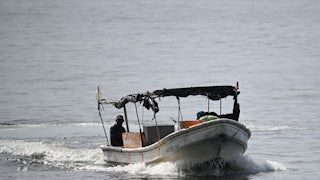 Fishermen sail on a boat in the water.