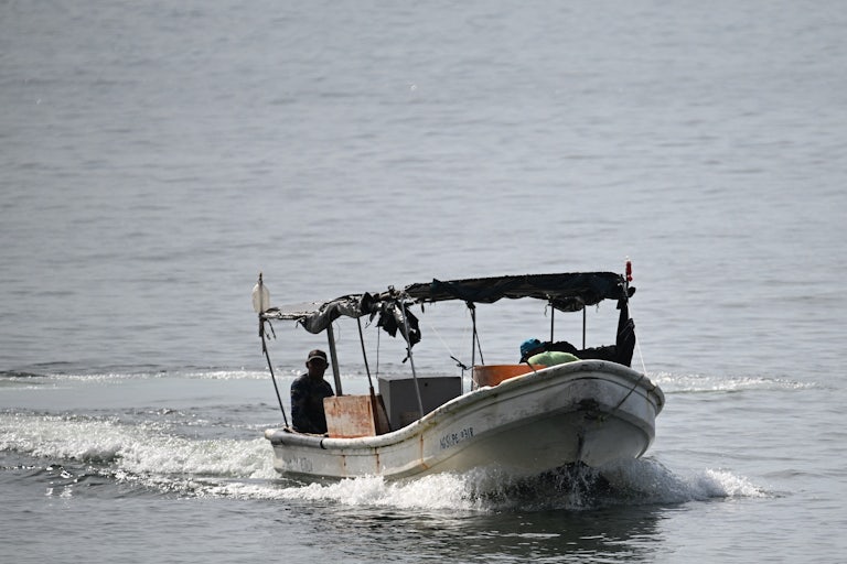 Fishermen sail on a boat in the water.