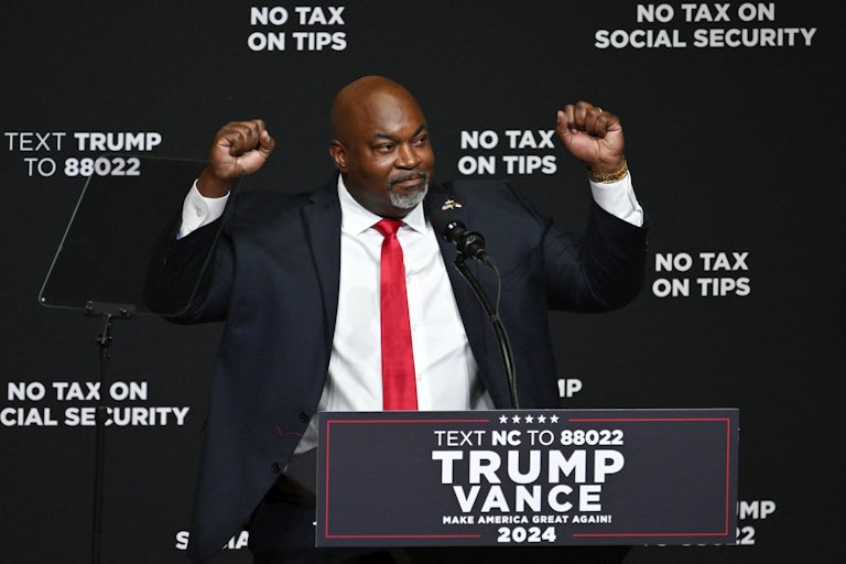 Mark Robinson raises his fists while standing at a podium during a Donald Trump rally