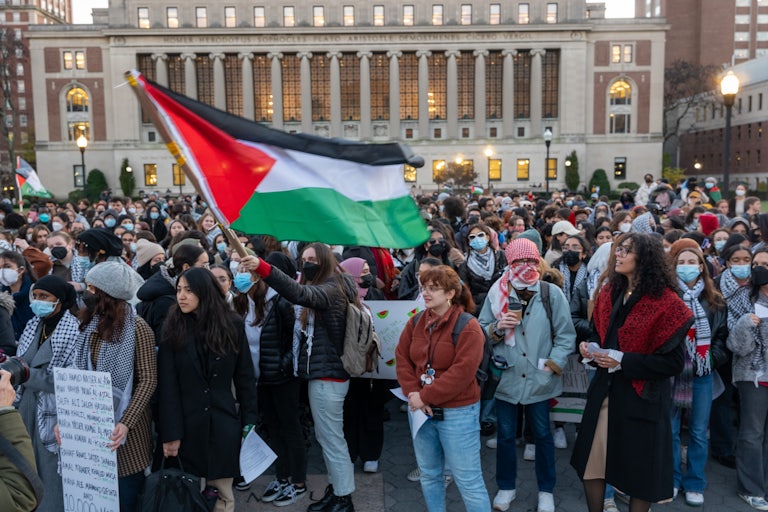 People hold protest signs and a Palestinian flag on Columbia University's campus