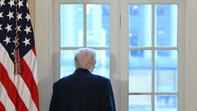 Donald Trump looks out a window in the Oval Office at the construction on the White House