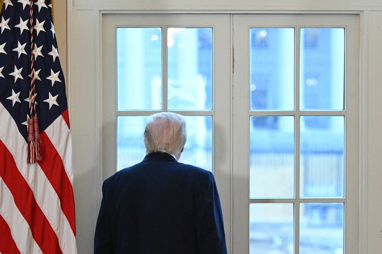 Donald Trump looks out a window in the Oval Office at the construction on the White House