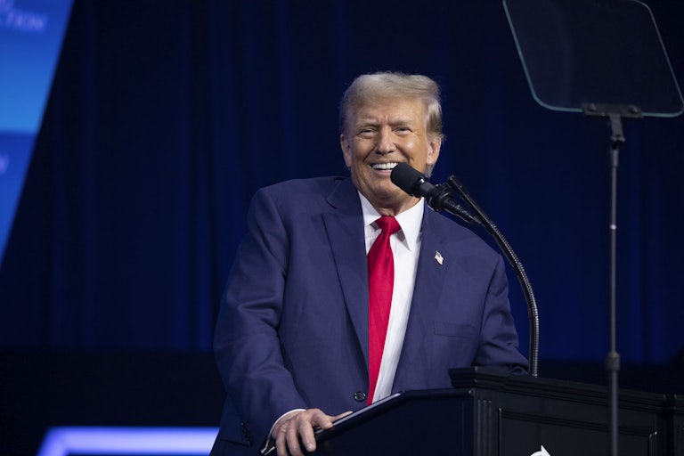Donald Trump smiles and stands before a lectern