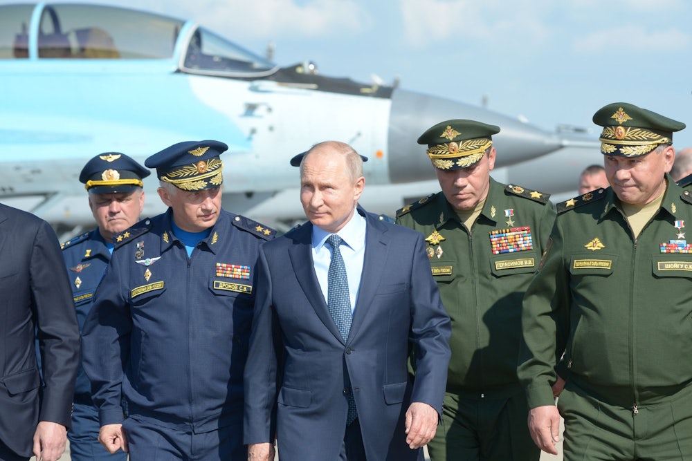 Russian President Vladimir Putin, surrounded by top military officers and officials, tours a military flight test center.