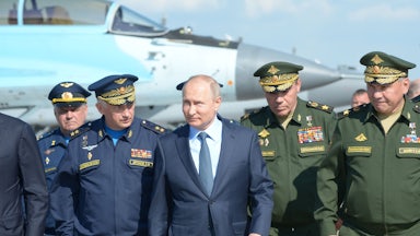 Russian President Vladimir Putin, surrounded by top military officers and officials, tours a military flight test center.