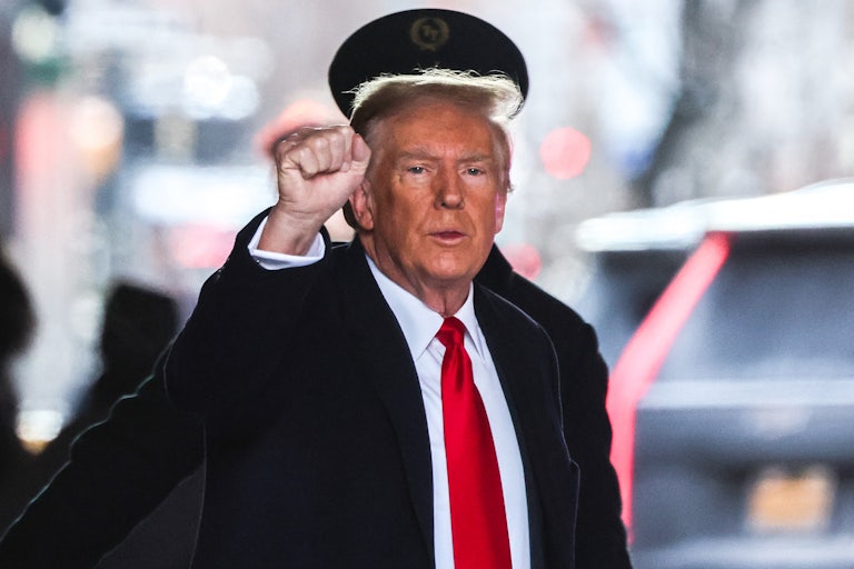 Donald Trump raises his hand up in a fist (presumably to the cameras) as he walks outside