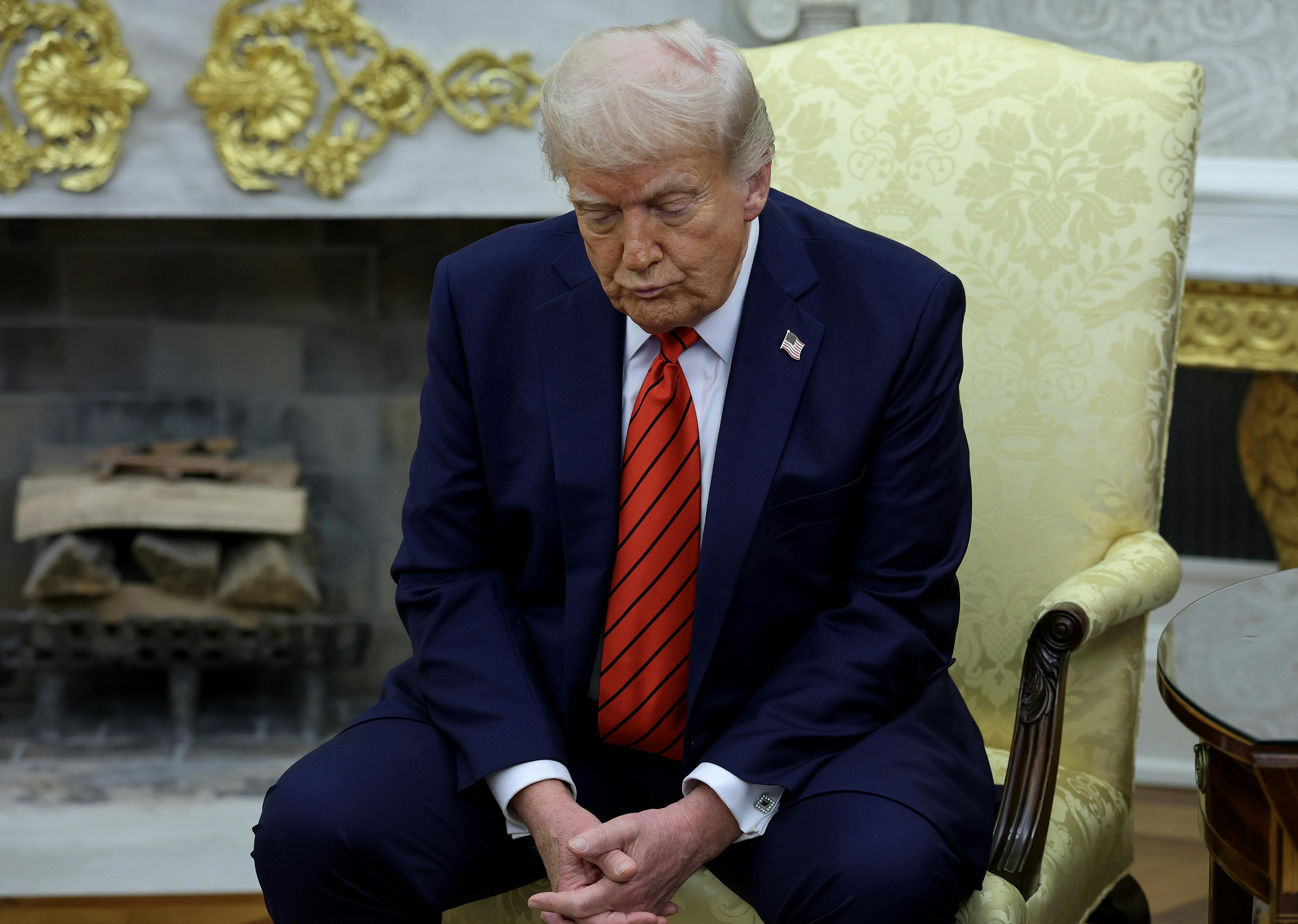Donald Trump sits slumped in a chair, forlornly looking at the floor.