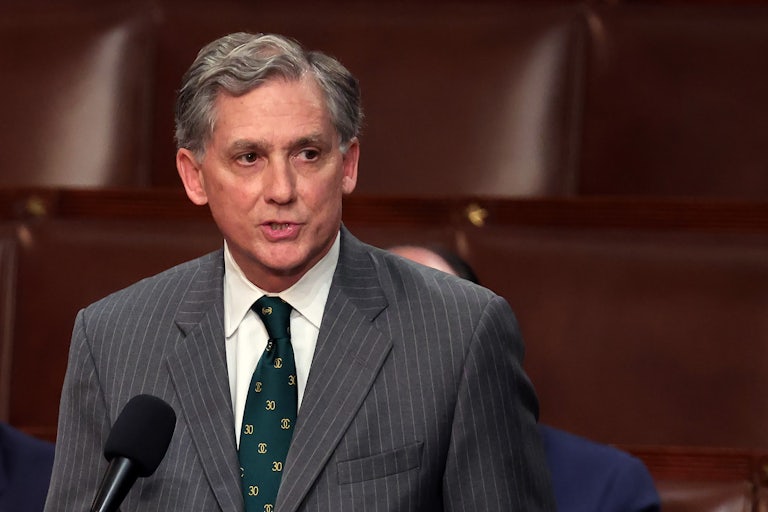 Representative French Hill wears a suit and speaks before a mic in the House chamber