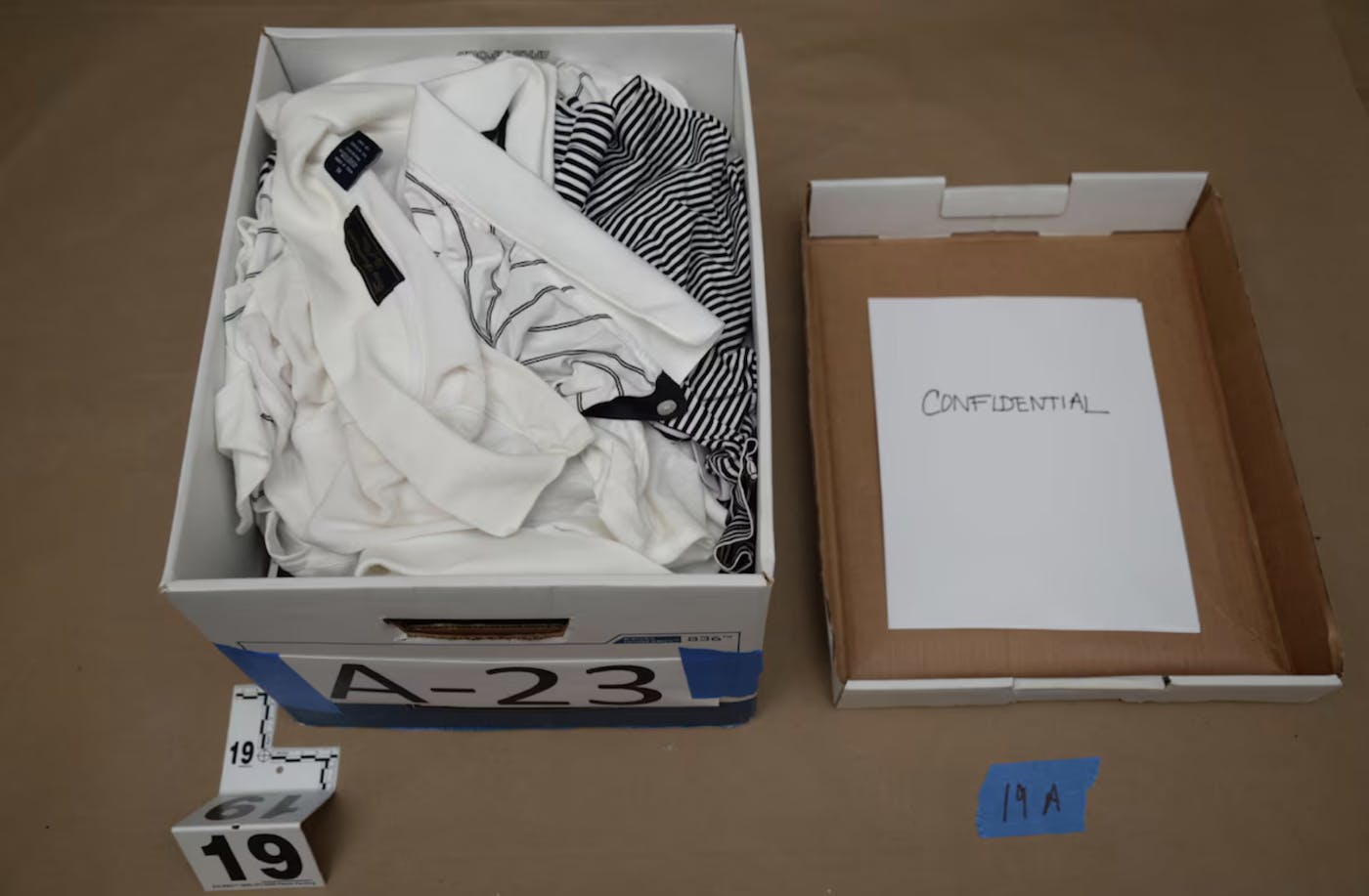 A box with golf shirts and a piece of paper that reads "CONFIDENTIAL"