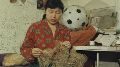 A photograph of the artist Ruth Asawa with one of her wire sculptures in 1961